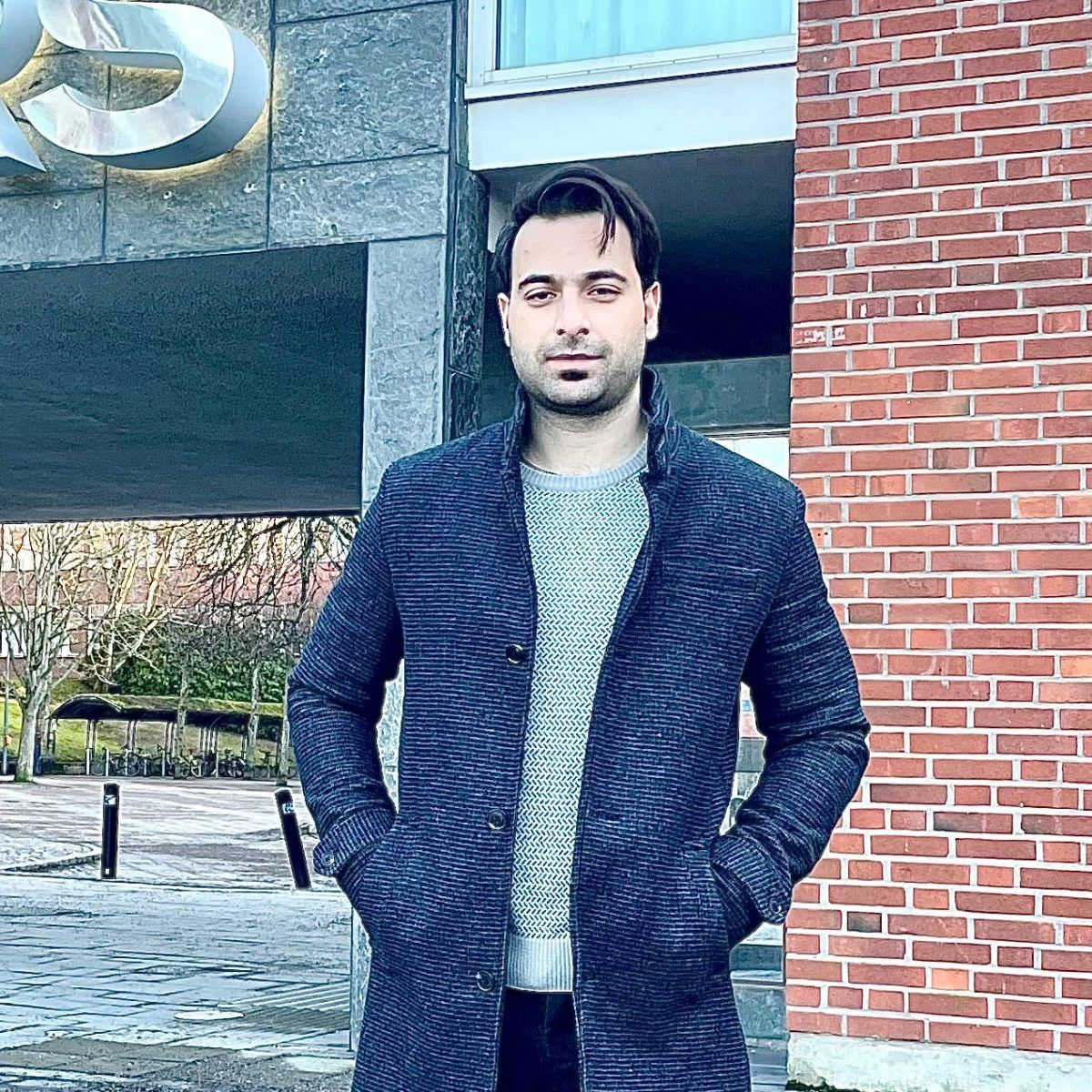 Photo of Munis Khan standing in front of a building.