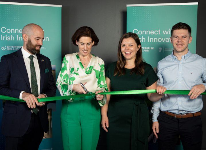 Two men and two women standing in a row. One woman is cutting a green ribbon at the opening of Nutritics Australian office.