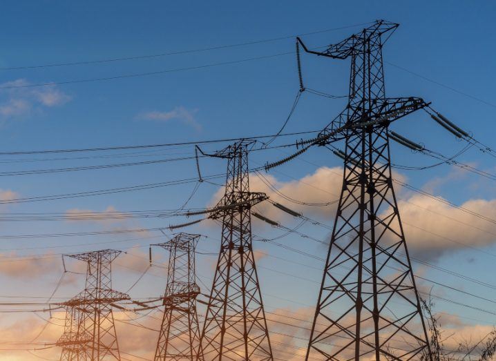 Electrical pylons with a blue sky behind them.