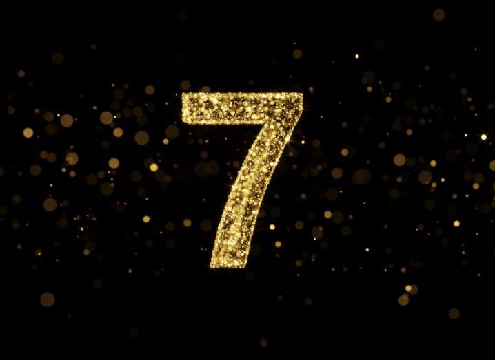 The number seven made out of gold glitter against a black background.
