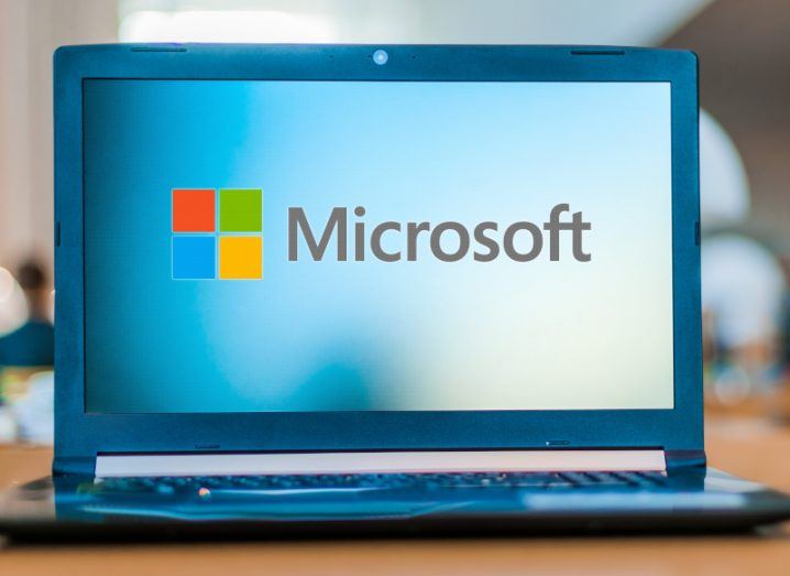 Microsoft company logo on a laptop screen, which is resting on a table.