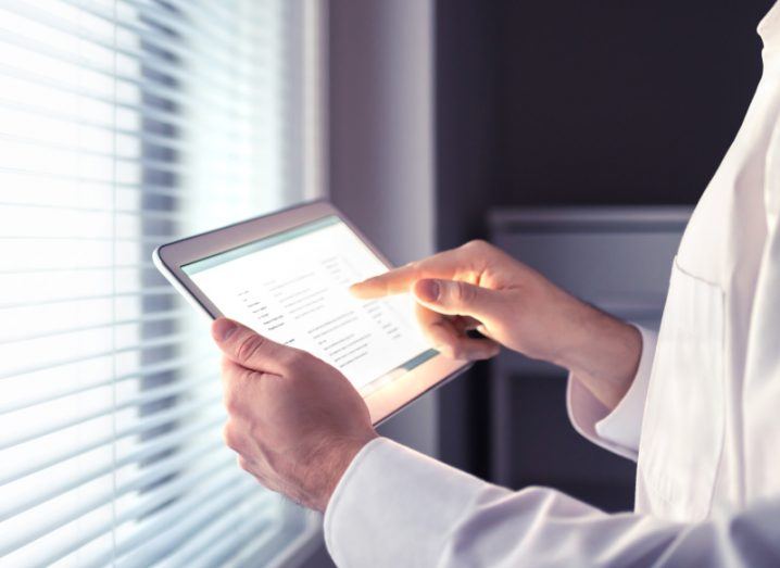 Medical worker looking at data on a tablet next to a window.