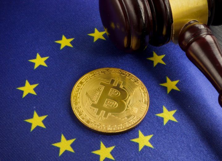 Bitcoin laying on an EU logo with a gavel next to it.