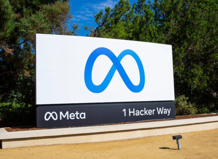 The logo of Facebook parent company Meta on a sign with trees and a blue sky behind it.