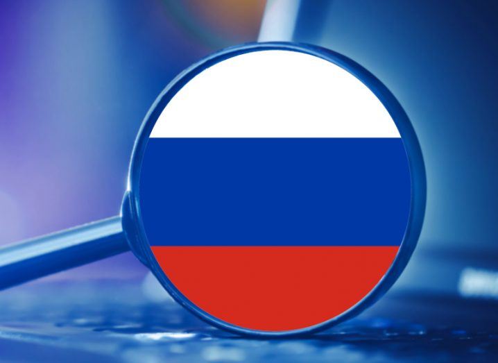 Flag of Russia in front of a laptop through a magnifying glass.