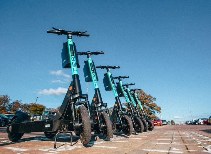A row of Tier s-scooters parked in a car park.
