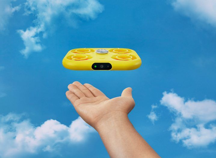 Snapchat Pixy flying in the air with an outstretched hand below it and clouds in the background.