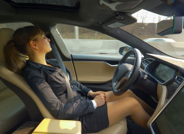 Sleeping woman seated in the driver's seat in an autonomous car.