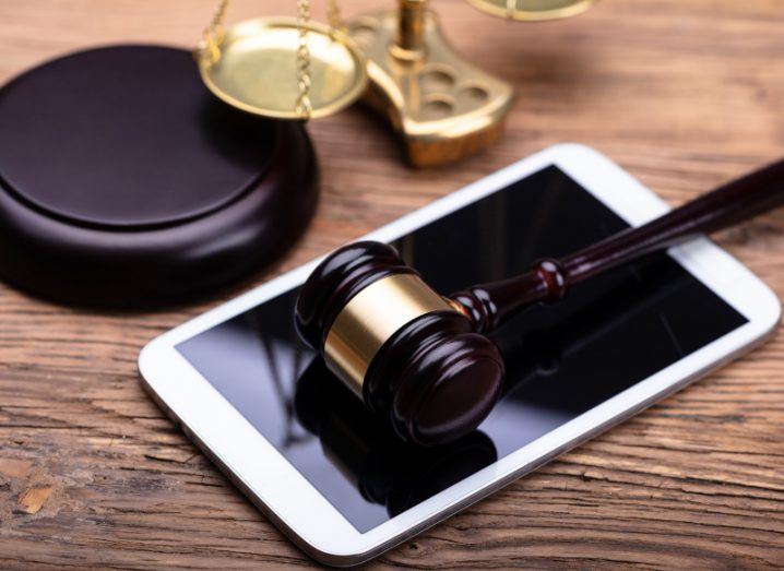 A judge’s gavel resting on a white smart phone on a wooden table, representing a legal ruling on mobile phone data.