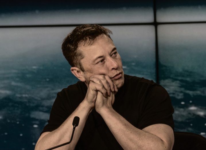 Elon Musk sitting down with a microphone in front of him.