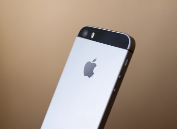 Photograph of an iPhone tilted at a slight angle, in a brown background.