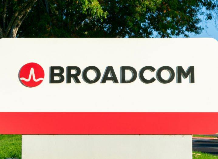Photograph of the Broadcom logo and name on a small billboard, standing on grass with a tree in the background.