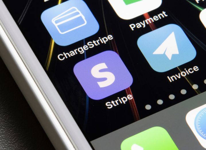 Stripe app on a mobile phone screen, next to other applications. The phone is resting on a black table background.