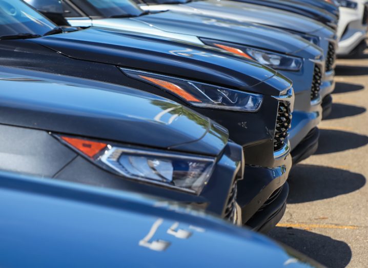 Photograph of multiple cars lined up in a parking lot.