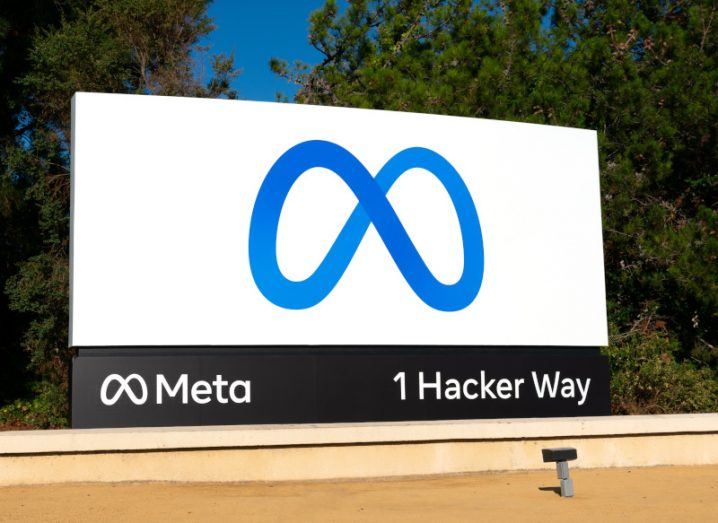 Meta sign logo in front of trees, with 1 Hacker Way written on the bottom of the sign.