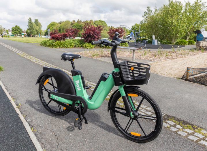 Bolt electric bike in Doorly Park in Sligo, resting on a cycle lane with a pedestrian path next to it, with trees in the background.
