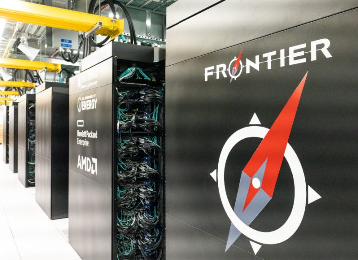 Photograph of large computer containers next to each other, with the closest featuring the logo for Frontier, a supercomputer in the US.