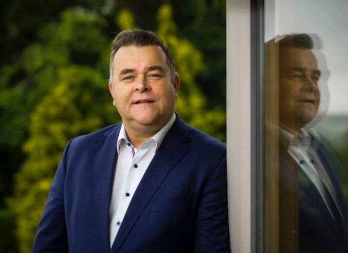 Brendan Kavanagh, CEO of Olive Group, standing next to a pane of glass with his reflection showing in the glass.