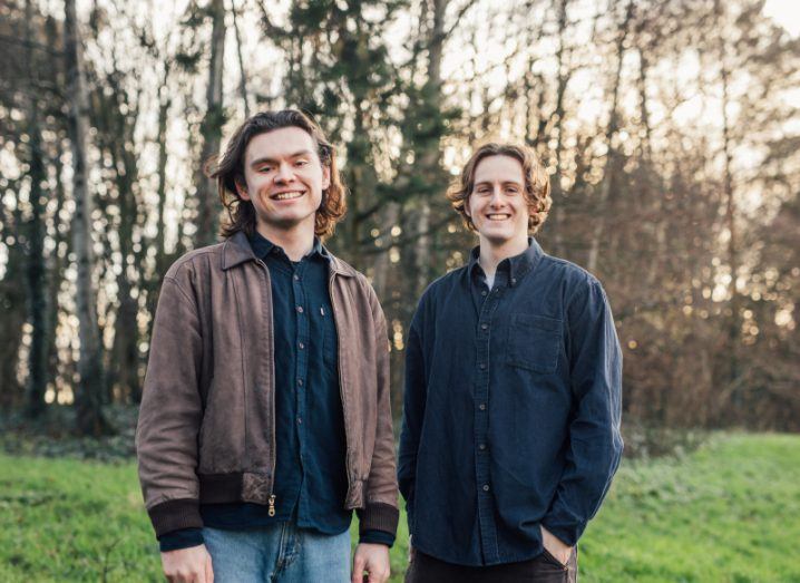 Two men smile at the camera while standing next to each other on green grass with some trees behind them. They are CropSafe founders John McElhone and Micheal McLaughlin.