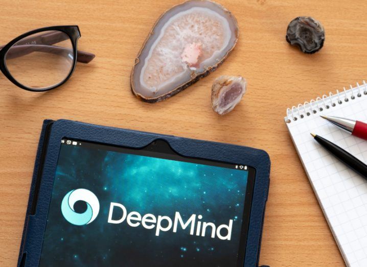 DeepMind logo displayed on a tablet on a table with an assortment of other items around it.