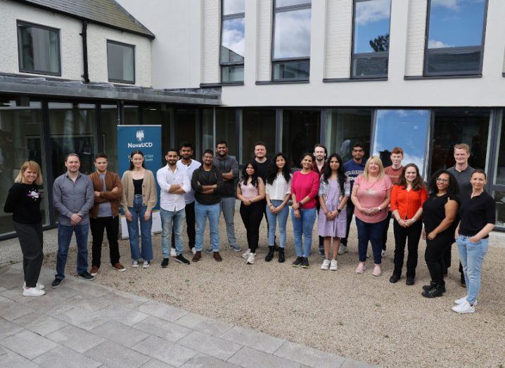 A group of students are standing in a semi-circular line in front of a building at NovaUCD.