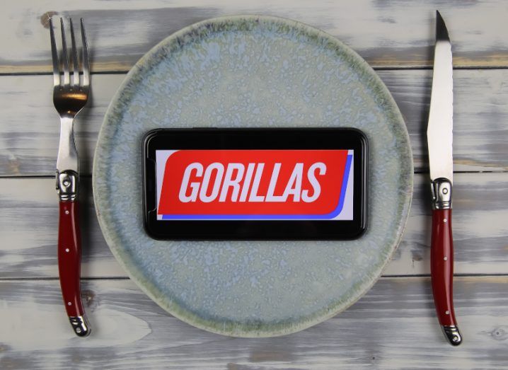 A plate with a smartphone displaying the Gorillas logo. Cutlery is on either side of the plate.