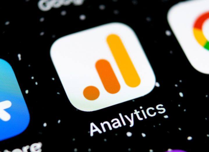 A close-up of a mobile screen with the Google Analytics app in the centre of a dark background. There are other apps visible next to it.
