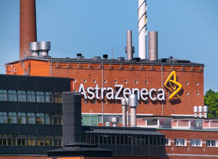 AstraZeneca manufacturing centre with red brick facade and logo. A blue sky can be seen in the background.