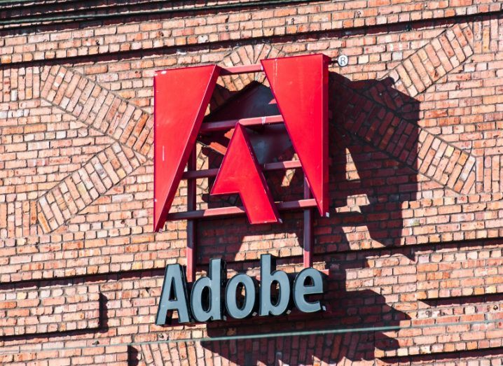 Adobe logo emerging from the side of a red-brick building.