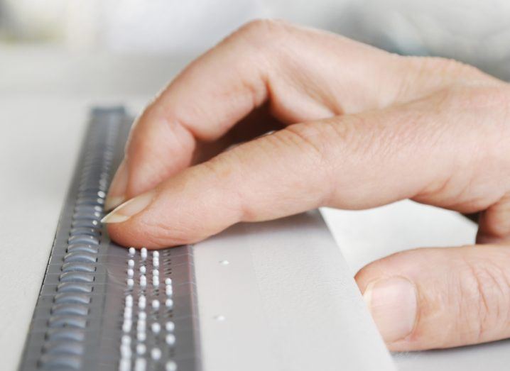 Person's hand using assistive tech for visually impaired people.