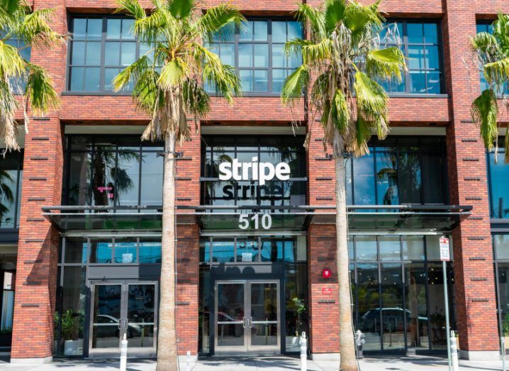 Brown building with windows and trees in front. The Stripe company logo is in the middle of the image.