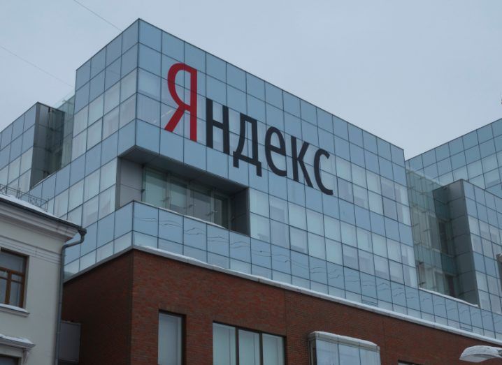 The Yandex logo written in Russian on an office building with a grey sky hanging over it.