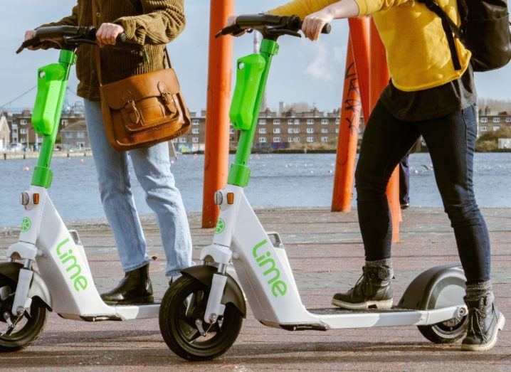 Two people using Lime e-scooters in Ireland outdoors.