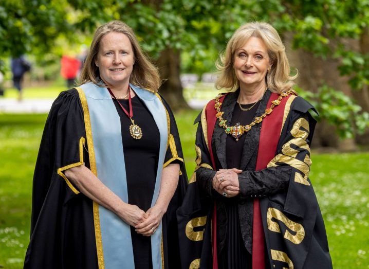 Prof Deborah McNamara and Prof Laura Viani stand outdoors in a green area wearing presidential regalia.