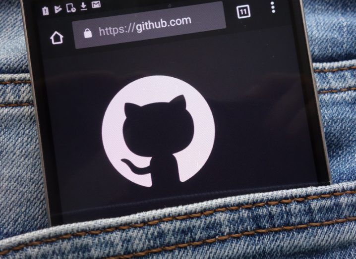 GitHub logo displayed on a smartphone screen inside the pocket of a pair of jeans.