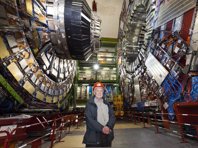 Peter Higgs stands in a helmet at a CERN facility.