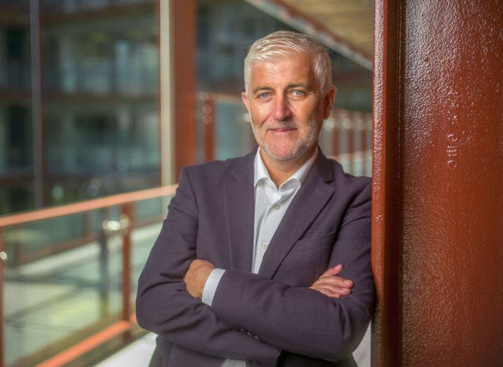 A headshot of Ronan Murphy, CEO of CWSI, leaning against a steel beam in an office space.
