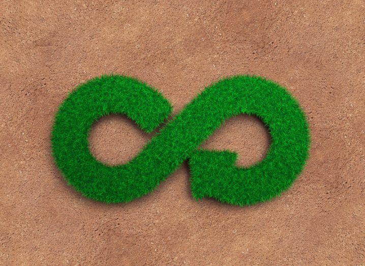 A green infinity symbol made of grass in a brown soil background, used to represent the circular economy.