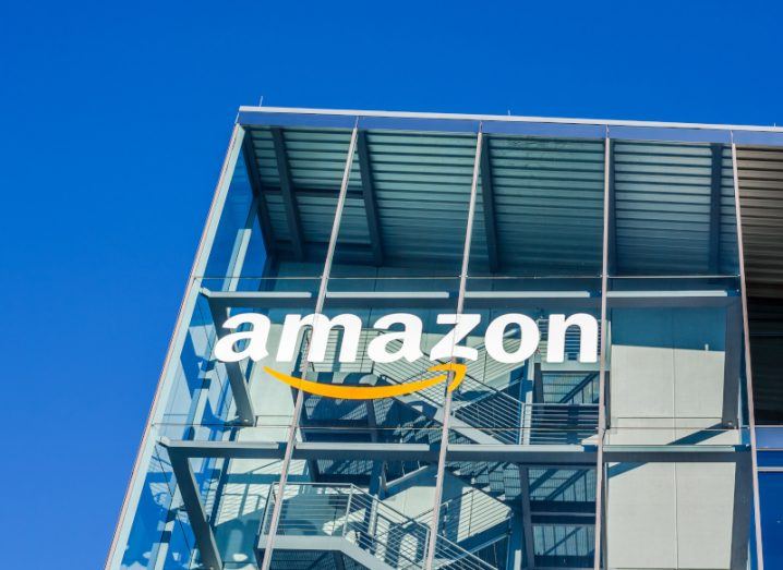 Amazon logo on a windowed building with a blue sky above it.