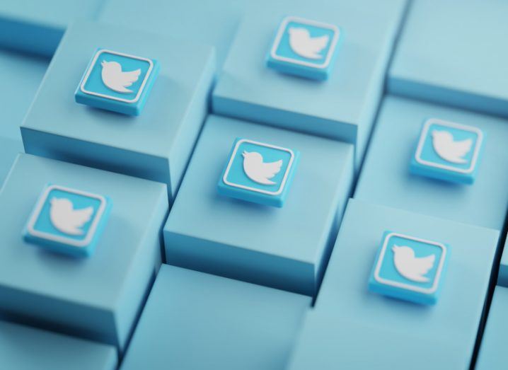 Twitter logo in white on blue tiles that are resting on a set of blue cubes.