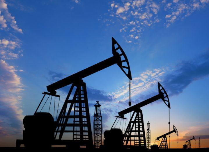 Silhouettes of crude oil pumps with a blue sky and a sunset background.