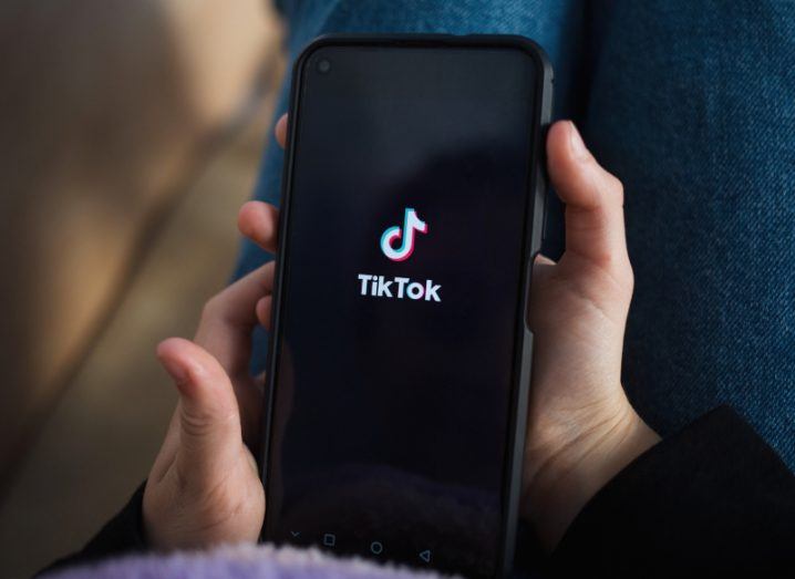 A childs hands holding a phone with TikTok open on it.
