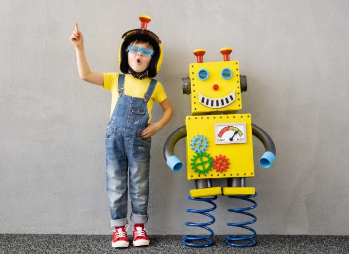 A child with a toy yellow robot standing beside them.