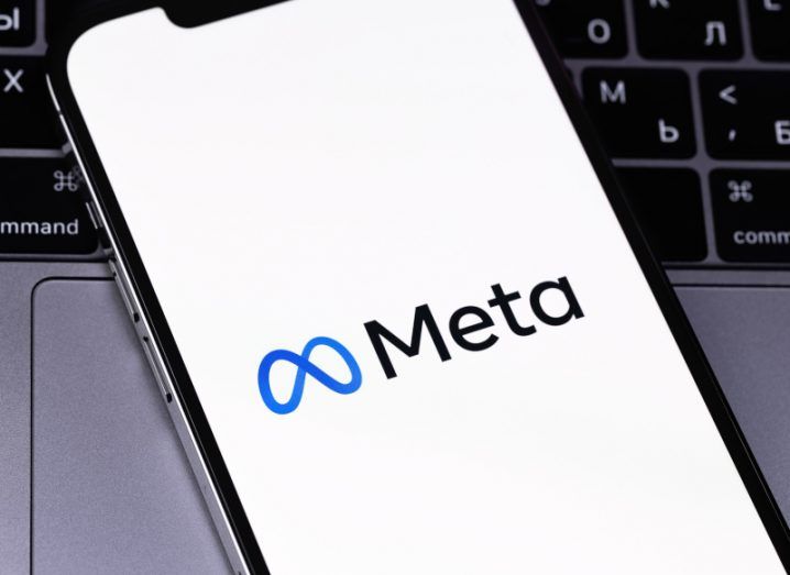 Mobile phone with the Meta logo on a white screen. The phone is resting on a laptop keyboard.
