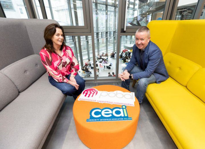 A man and a woman sitting on large couches with a small table between them. The table has the CEAI logo on it.