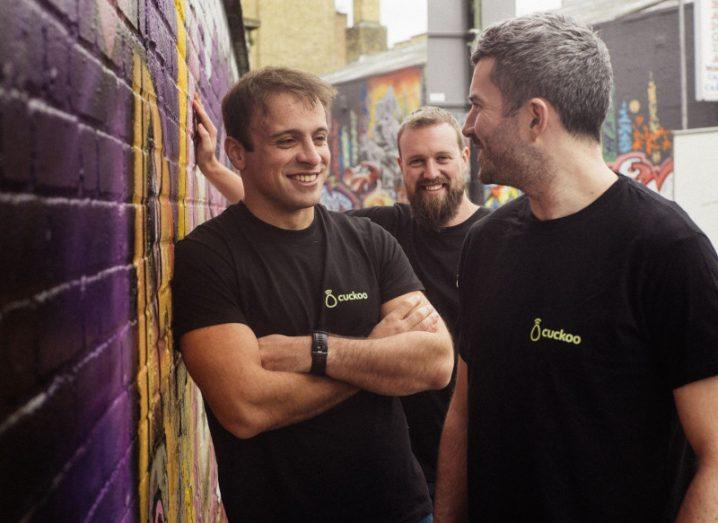 The founders of Cuckoo wear matching branded T-shirts as the laugh and chat next to a wall of graffiti.