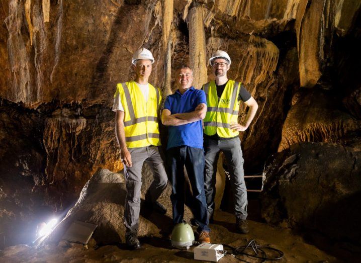 Three men standing in the middle of Mitchelstown cave. One of them is wearing a blue shirt and is the owner. The other two are in high visibility vests and work with the Irish National Seismic Network.