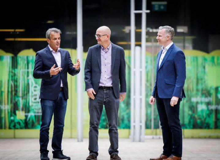 Three men in suits standing and talking to each other with a building and white poles in the background. They are the CEOs of Viatel, SupportIT and ActionPoint.
