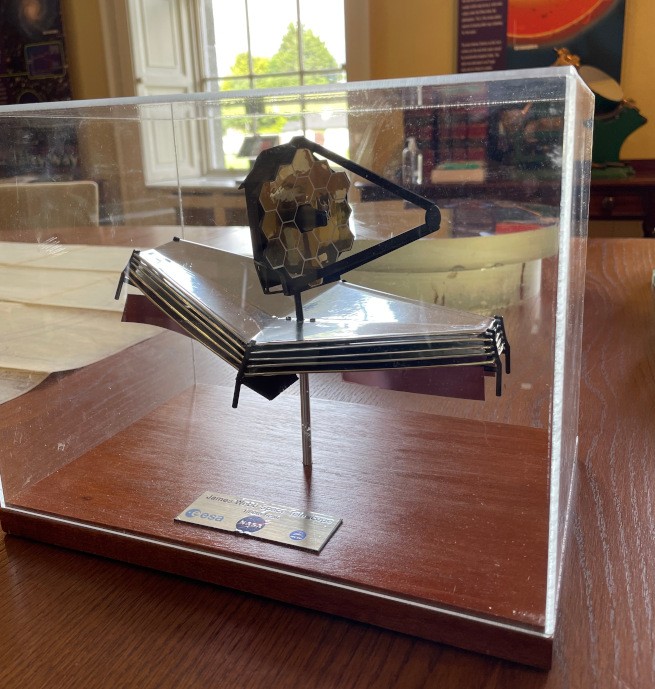 A miniature model of the James Webb telescope in a glass case.