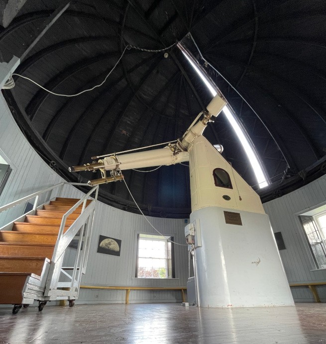 Wide-angle shot of a large telescope with a flight of stairs leading up to the viewing lenses.